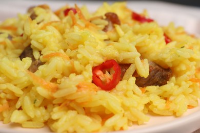 Photo of Delicious pilaf with meat on white plate, closeup