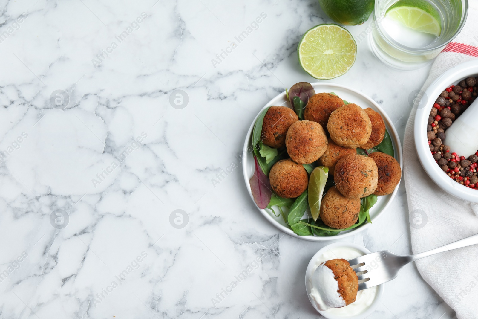 Photo of Delicious falafel balls with herbs and lime on white marble table, flat lay. Space for text