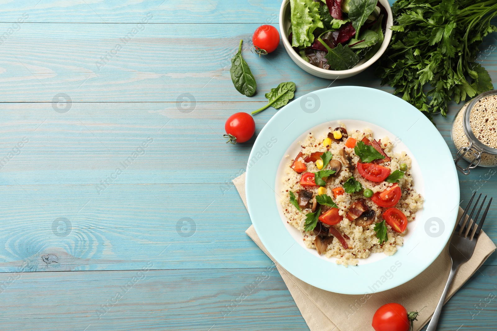 Photo of Plate of tasty quinoa porridge with fried bacon, mushrooms and vegetables on light blue wooden table, flat lay. Space for text