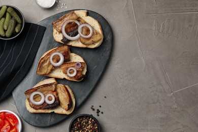 Photo of Tasty fried pork lard with bread slices and onion on grey table, flat lay. Space for text