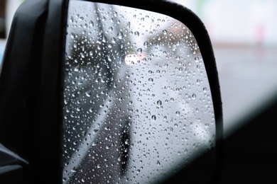 Photo of Closeup of car side rear view mirror with rain drops