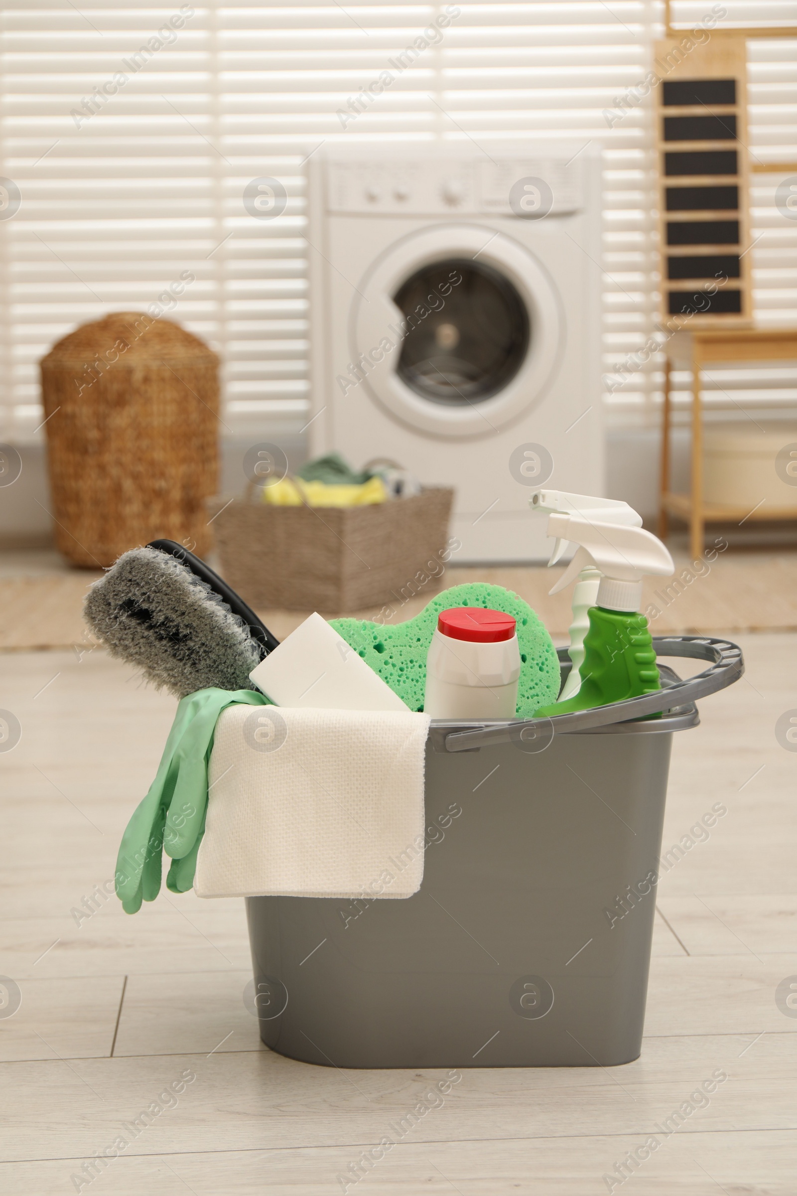 Photo of Different cleaning products in bucket on floor indoors