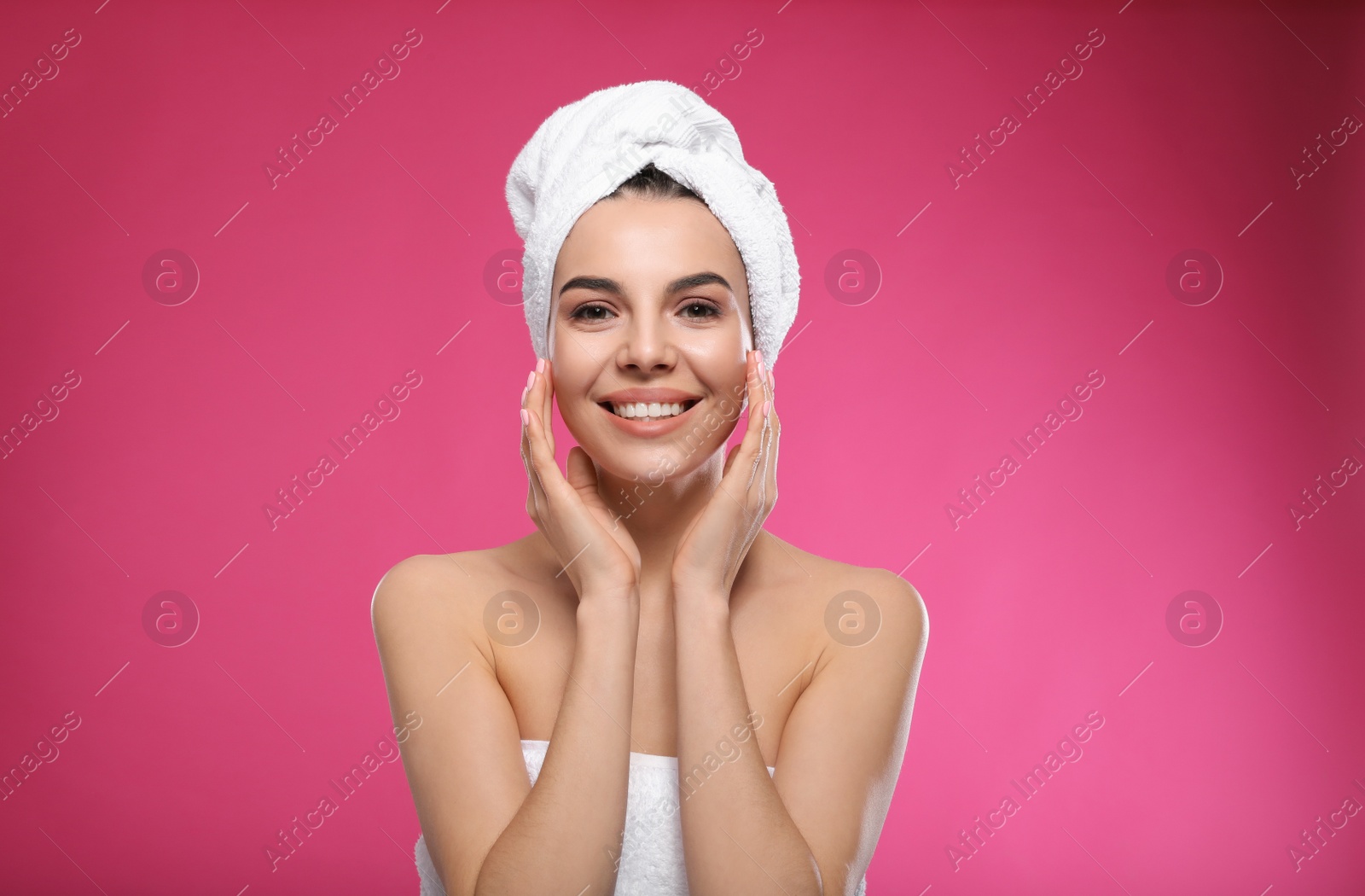 Photo of Happy young woman with towel on head against pink background. Washing hair