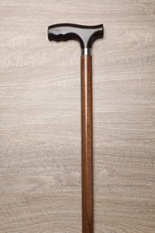Elegant walking cane on wooden table, top view