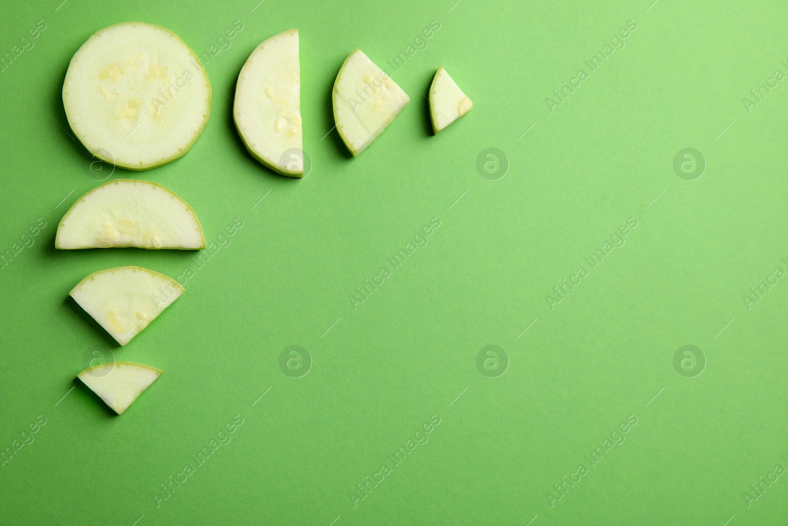 Photo of Fresh ripe cut zucchini on green background, flat lay. Space for text