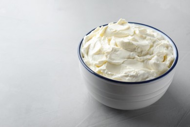 Bowl of tasty cream cheese on grey table. Space for text