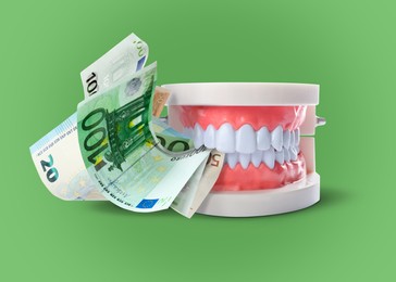 Image of Model of oral cavity with teeth and euro banknotes on green background. Concept of expensive dental procedures