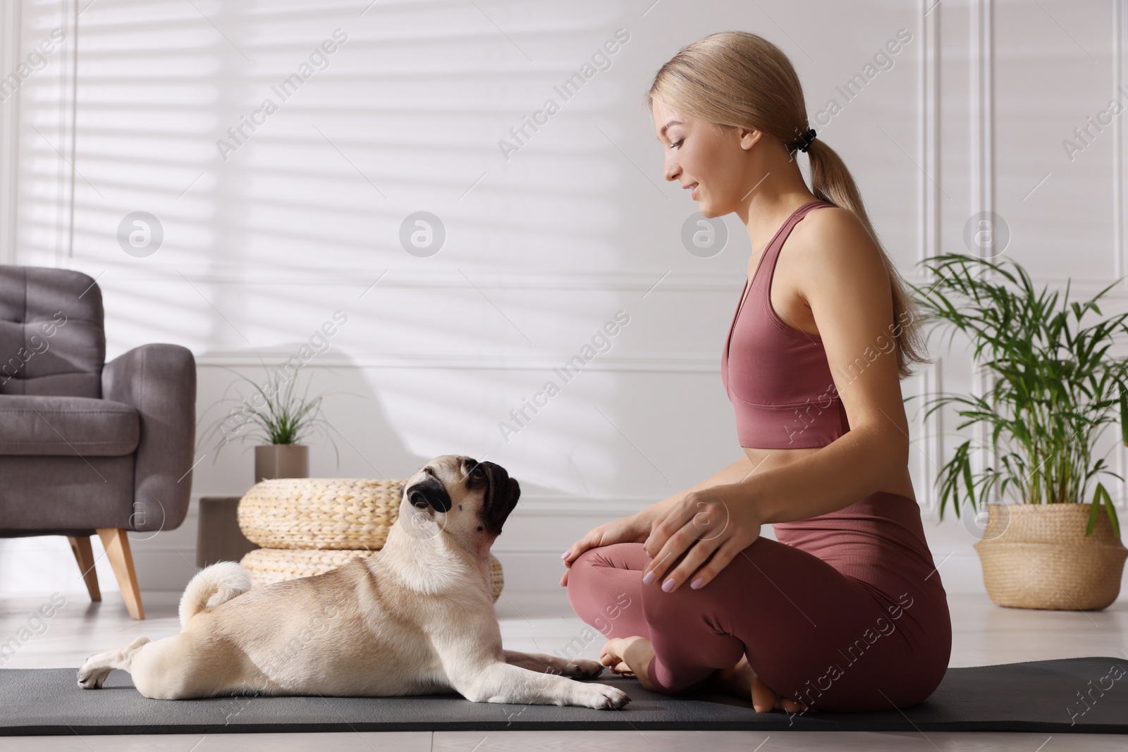 Photo of Beautiful woman with dog practicing yoga at home