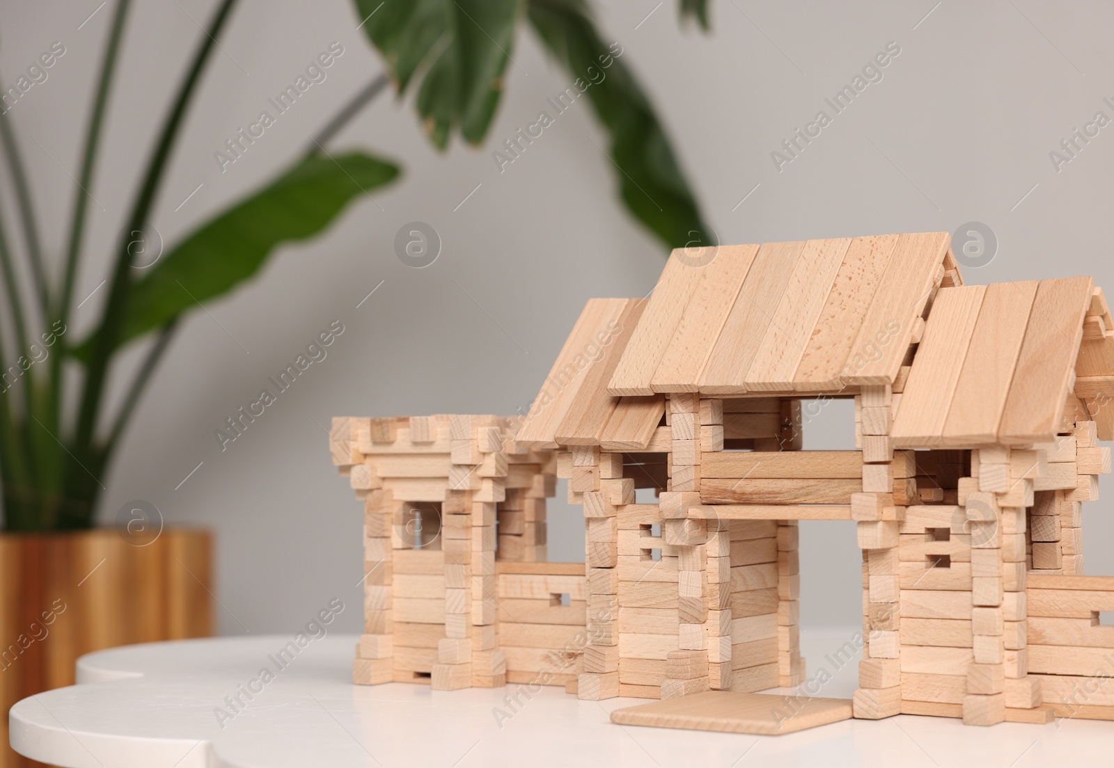 Photo of Wooden entry gate on white table against blurred background, space for text. Children's toy