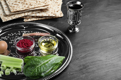 Photo of Passover Seder plate (keara) with traditional meal on black table, space for text. Pesah celebration