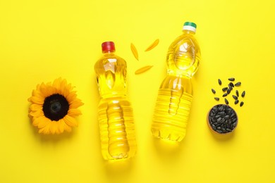 Photo of Bottles of cooking oil, sunflower and seeds on yellow background, flat lay