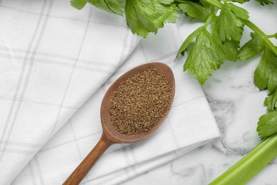 Photo of Spoon of celery seeds and fresh plant on white marble table, flat lay