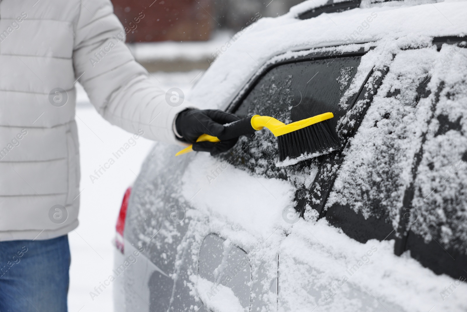 Photo of Man cleaning snow from car outdoors, closeup