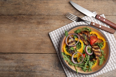 Photo of Delicious salad with roasted eggplant and arugula served on wooden table, flat lay. Space for text