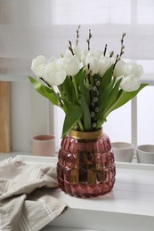 Photo of Beautiful bouquet of willow branches and tulips in vase indoors