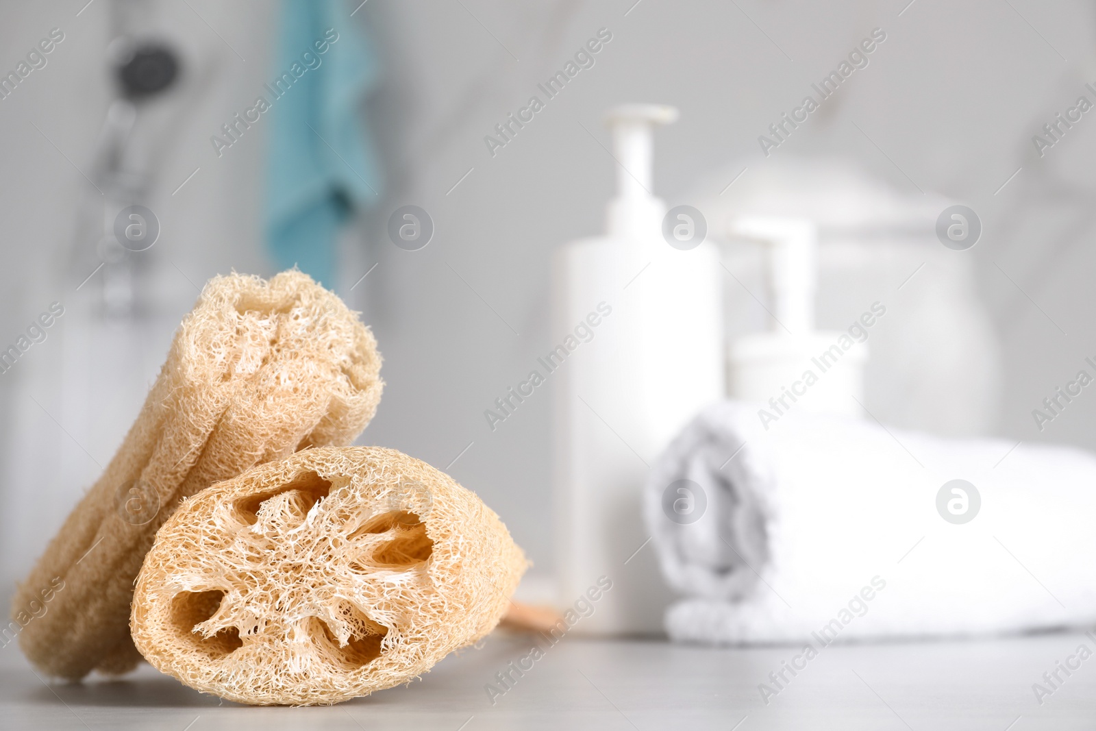 Photo of Natural loofah sponges on table in bathroom. Space for text