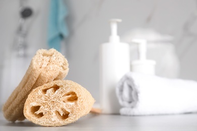 Natural loofah sponges on table in bathroom. Space for text