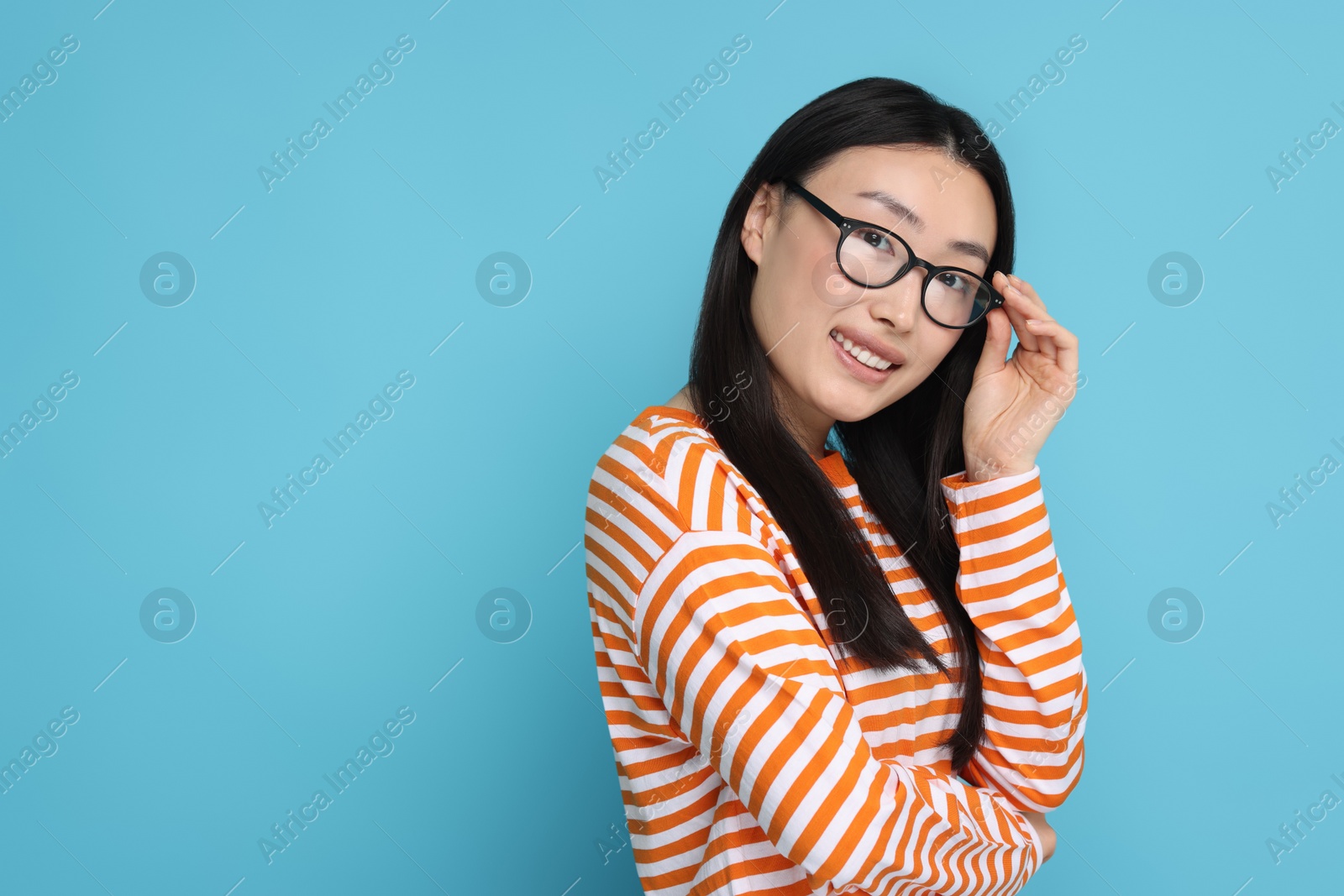 Photo of Portrait of happy woman in glasses on light blue background. Space for text