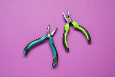 Photo of Two pliers on purple background, flat lay