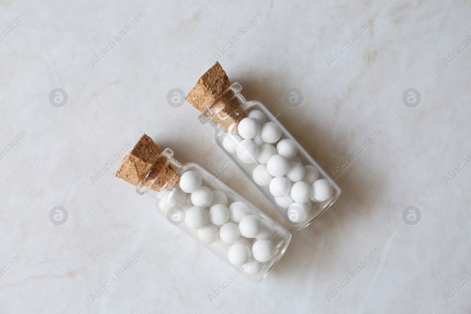 Photo of Bottles with homeopathic remedy on white table, flat lay