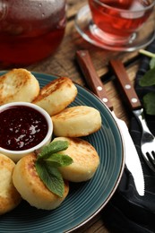 Delicious cottage cheese pancakes with jam and mint on wooden table