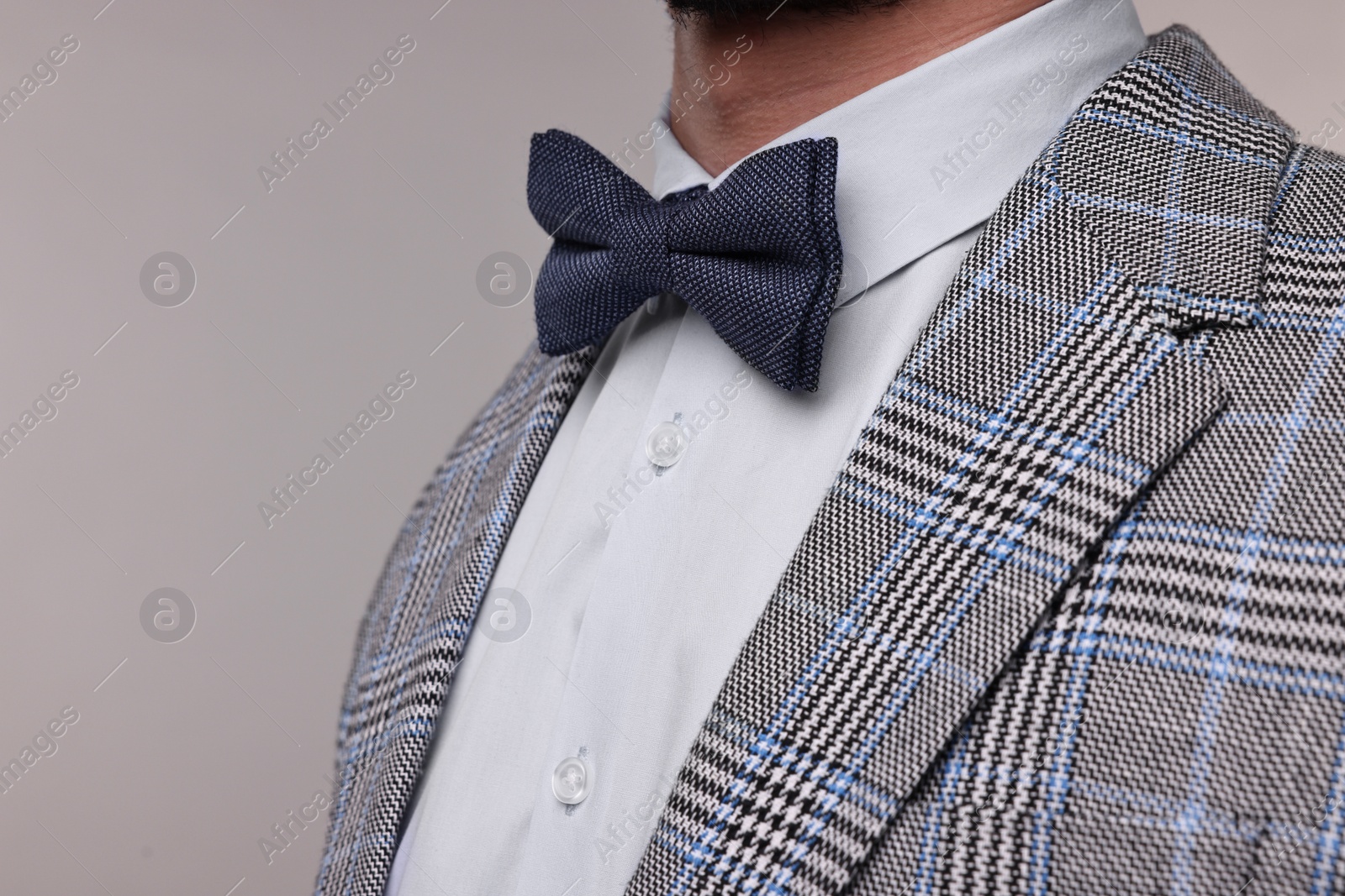 Photo of Man in suit, shirt and bow tie on grey background, closeup