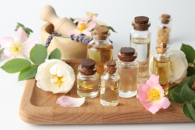 Aromatherapy. Different essential oils, flowers and green leaves on white table