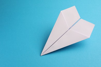 Photo of Handmade white paper plane on light blue background, space for text