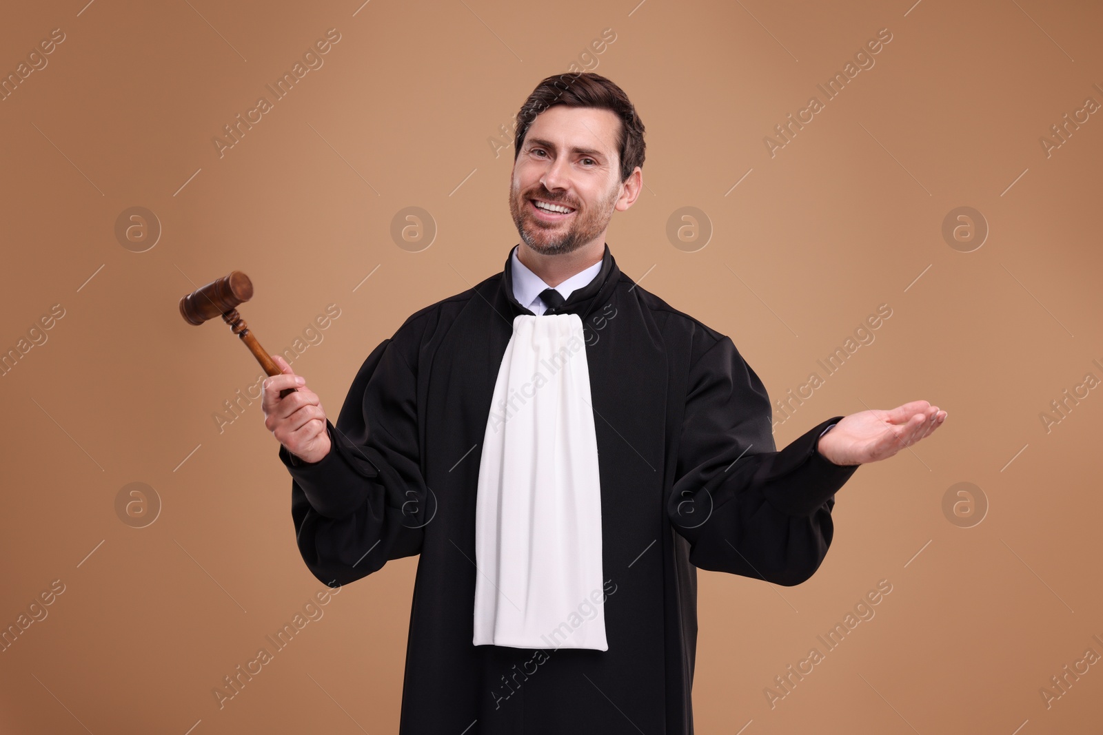 Photo of Smiling judge with gavel on light brown background