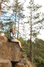 Photo of Young woman on rocky mountain near forest. Camping season