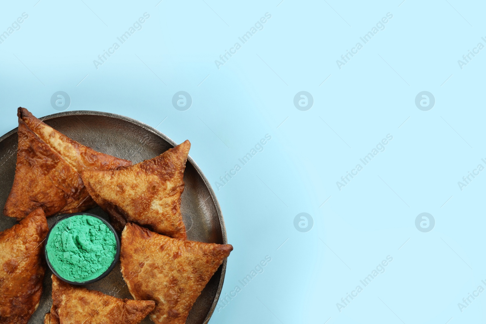 Photo of Top view of traditional Indian food and color powder dye on turquoise background, space for text. Holi festival