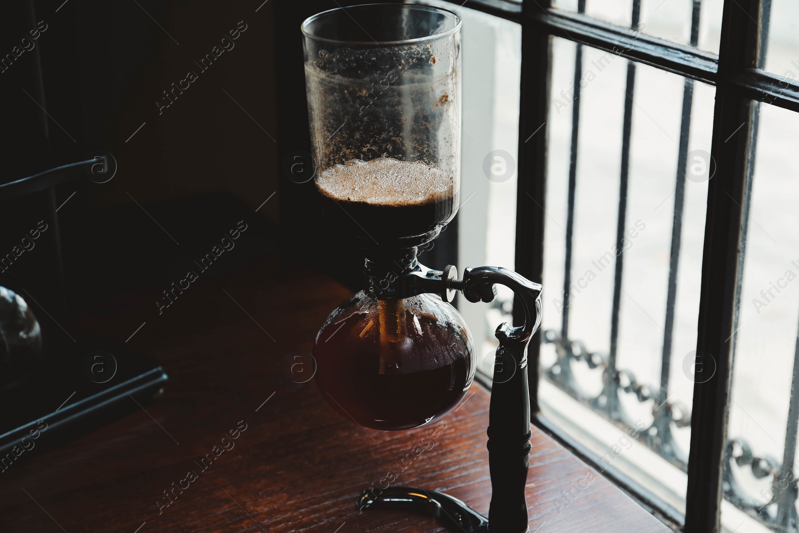 Photo of Vacuum coffee maker on wooden table in cafe