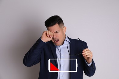 Tired man yawning and illustration of discharged battery on light grey background