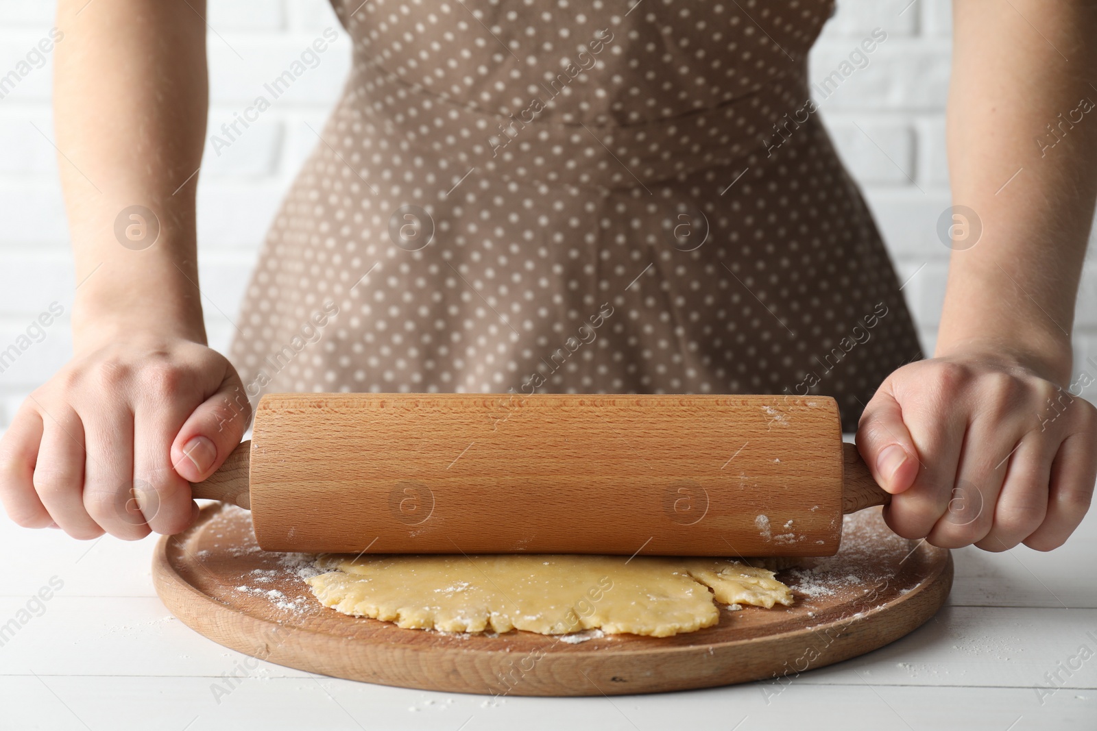 Photo of Making shortcrust pastry. Woman rolling raw dough at white wooden table, closeup