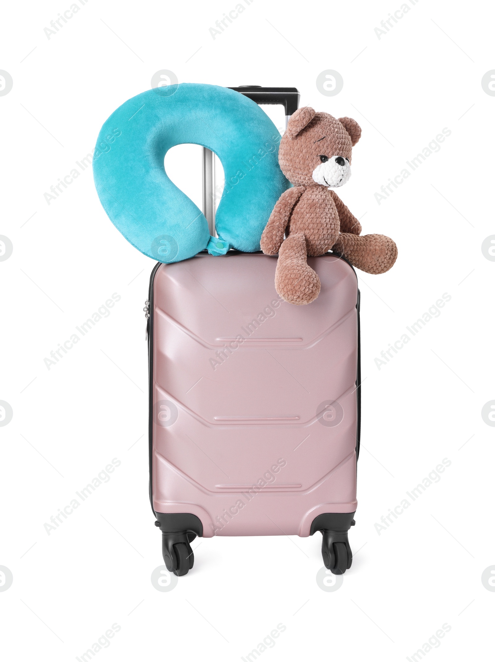 Photo of Light blue travel pillow and toy bear on suitcase against white background