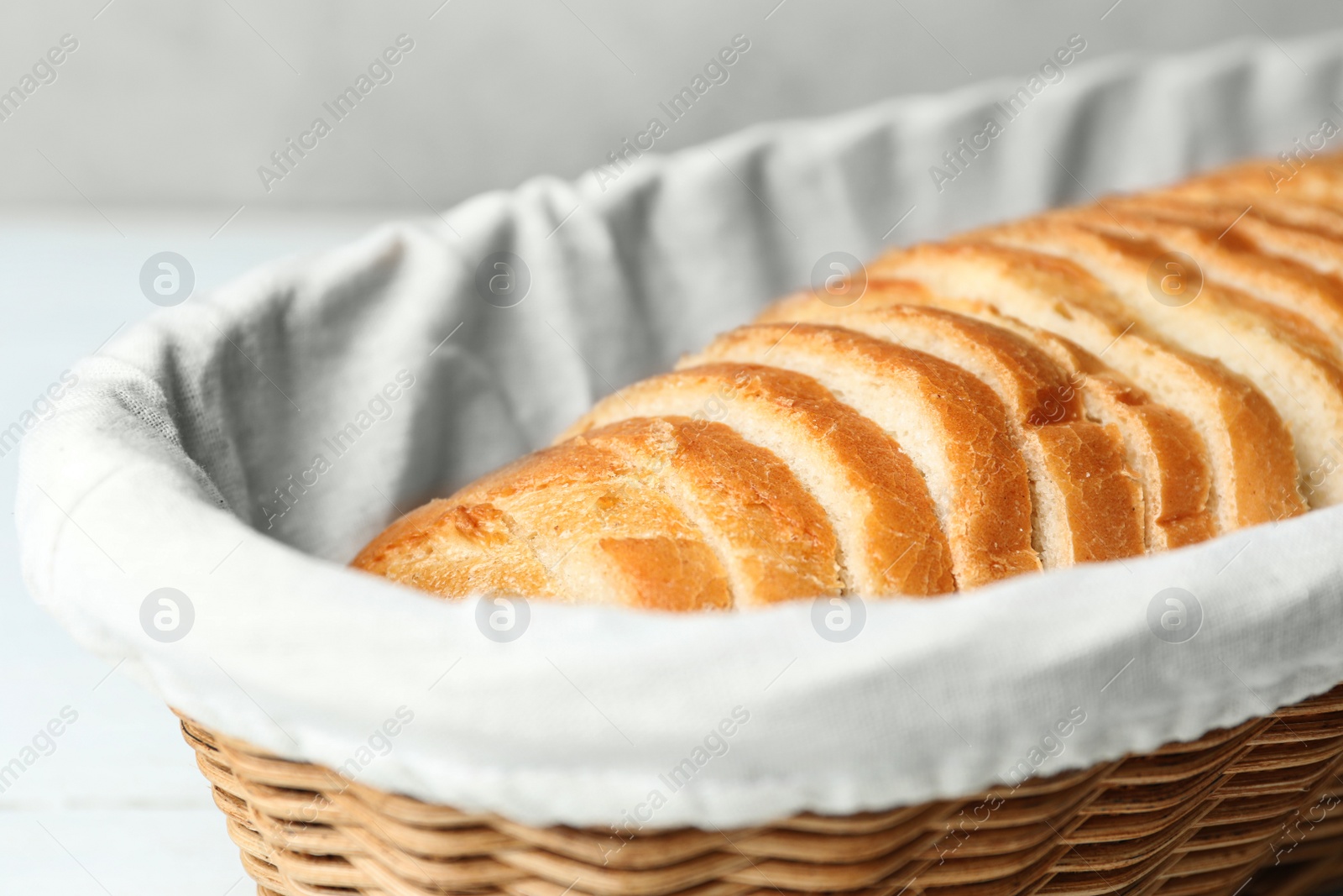 Photo of Slices of bread in basket on white table, closeup