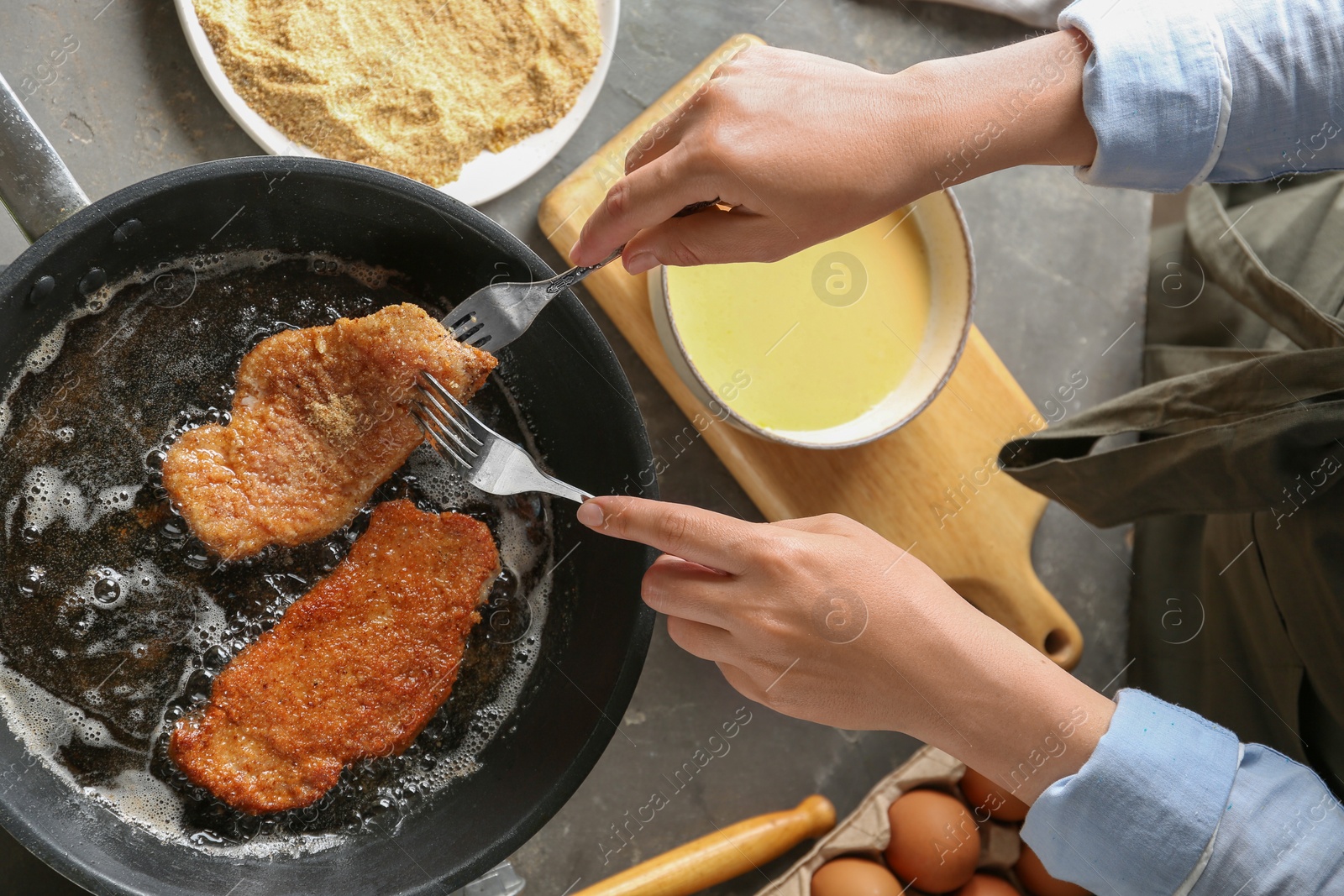 Photo of Woman cooking schnitzels in frying pan, top view