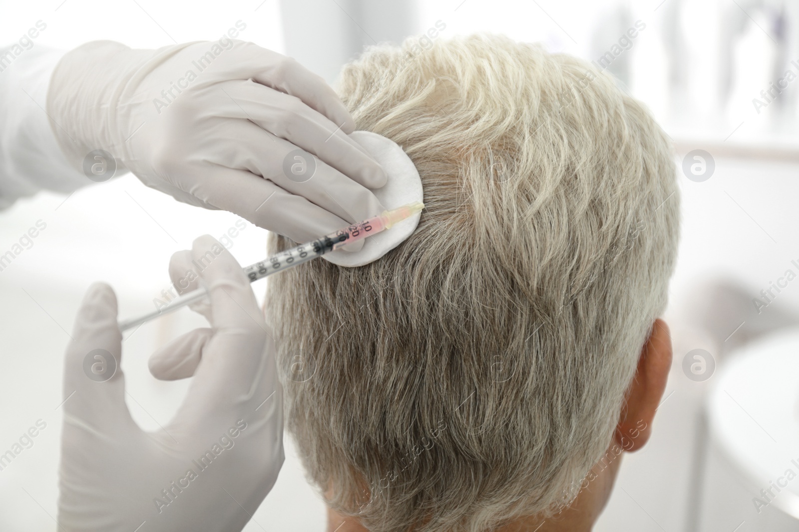 Photo of Senior man with hair loss problem receiving injection in salon