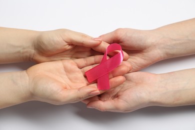 Women holding pink ribbon on white background, top view. Breast cancer awareness