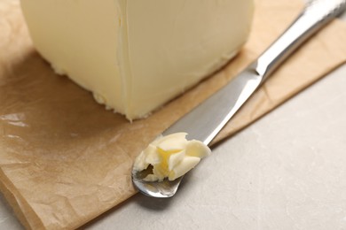 Photo of Block of tasty butter and knife on light table, closeup