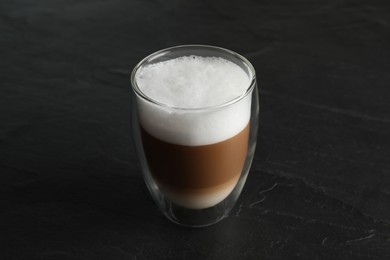 Hot coffee with milk in glass on black table