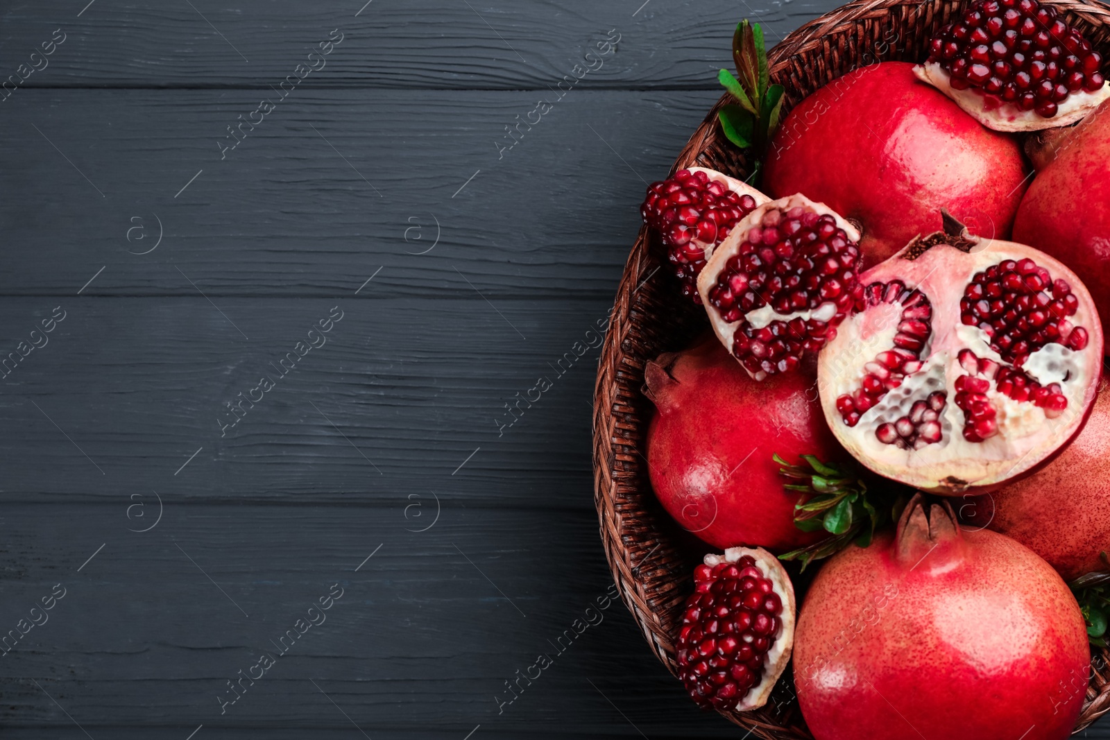 Photo of Delicious ripe pomegranates on grey wooden table, top view. Space for text