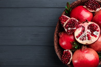 Photo of Delicious ripe pomegranates on grey wooden table, top view. Space for text