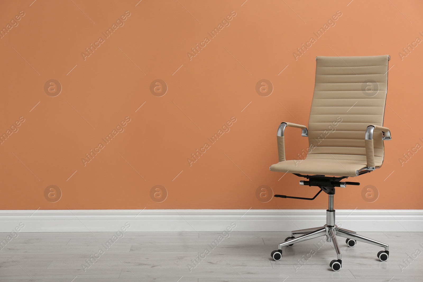 Photo of Modern office chair near orange coral wall indoors. Space for text