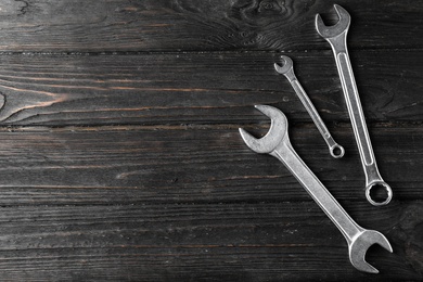 New wrenches on wooden background, top view with space for text. Plumber tools