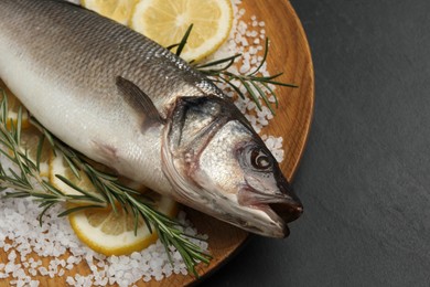Photo of Sea bass fish and ingredients on black table, closeup. Space for text