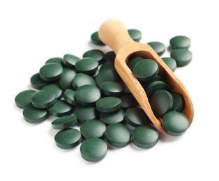 Photo of Scoop and spirulina tablets on white background