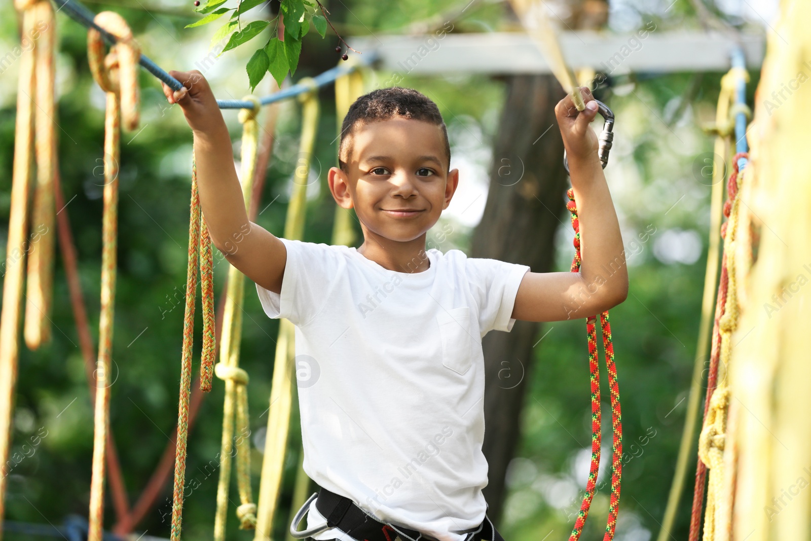 Photo of Little African-American boy climbing in adventure park. Summer camp