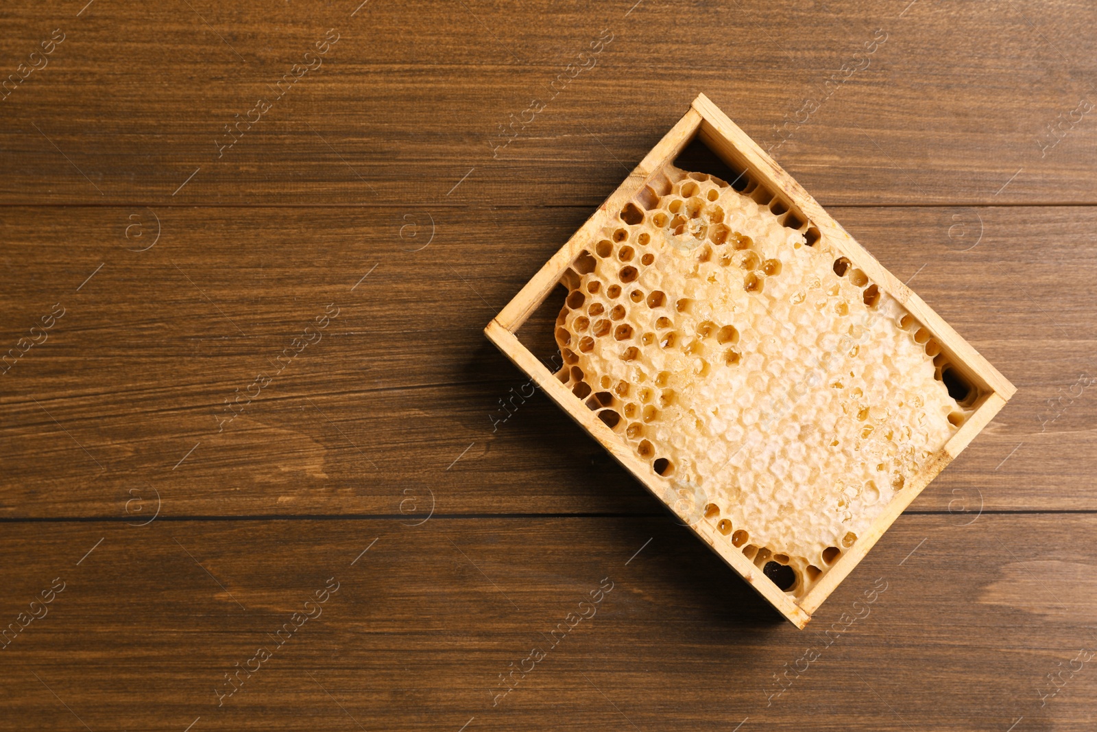 Photo of Honeycomb frame on wooden table, top view with space for text. Beekeeping tool