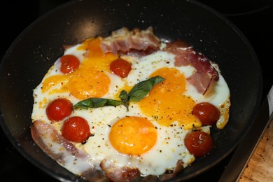 Photo of Tasty eggs with tomatoes and bacon in frying pan for breakfast, closeup